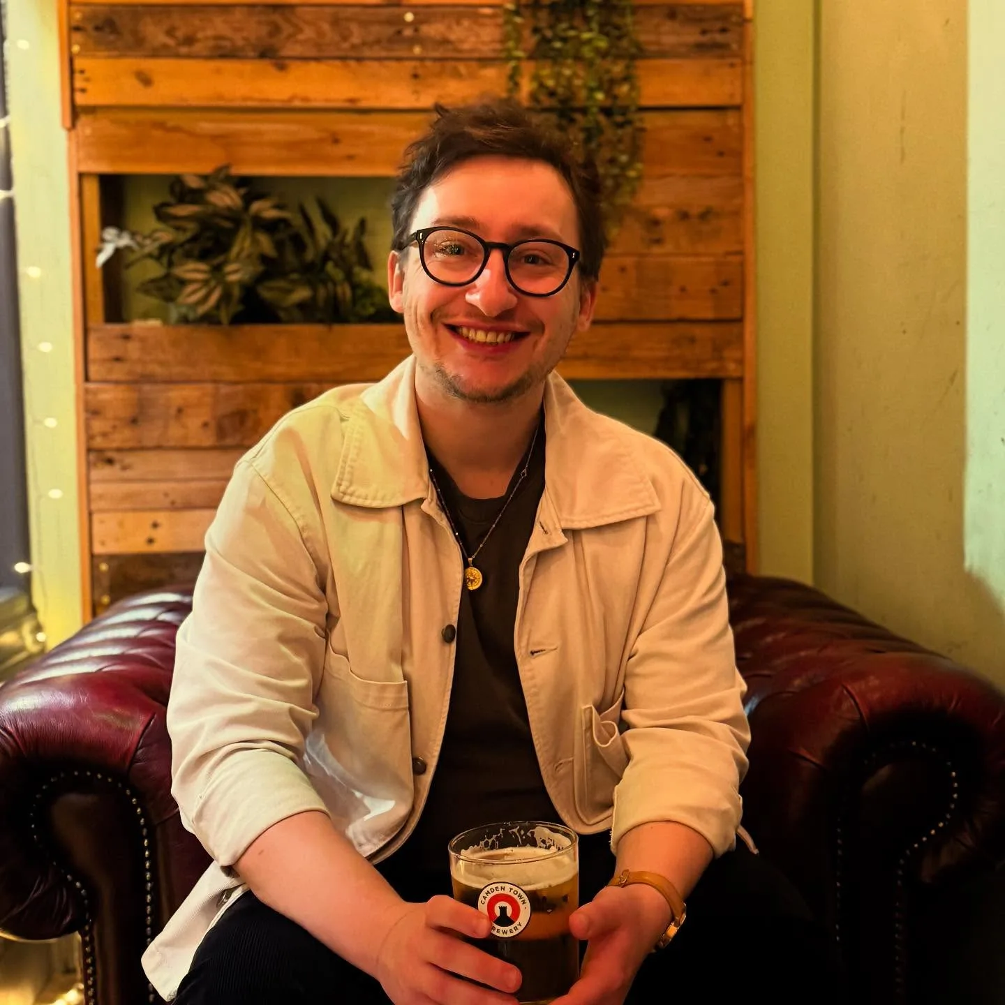 George relaxing on a Chesterfield sofa with a Camden Town beer